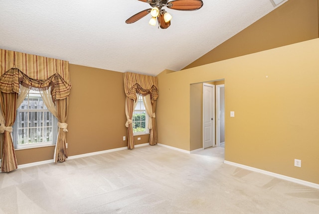 empty room featuring ceiling fan, lofted ceiling, and light carpet