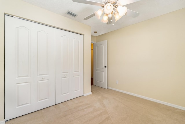 unfurnished bedroom with ceiling fan, a closet, and light colored carpet