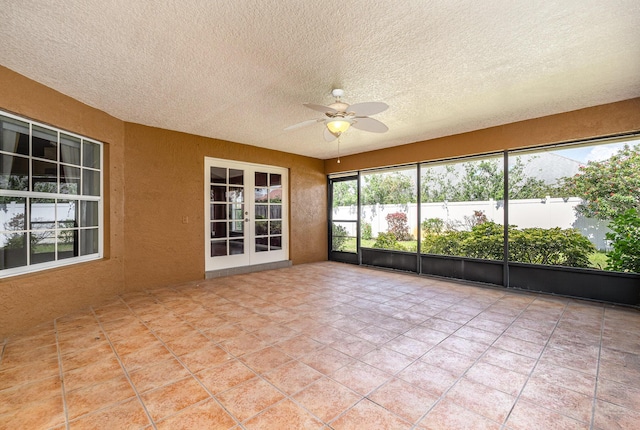 unfurnished sunroom featuring ceiling fan and french doors