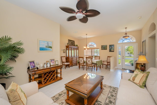 living room featuring ceiling fan with notable chandelier and light hardwood / wood-style floors