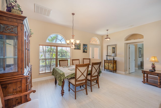 dining space featuring a wealth of natural light, an inviting chandelier, and light wood-type flooring