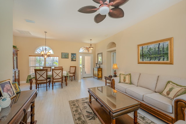 living room featuring ceiling fan with notable chandelier, french doors, and light wood-type flooring