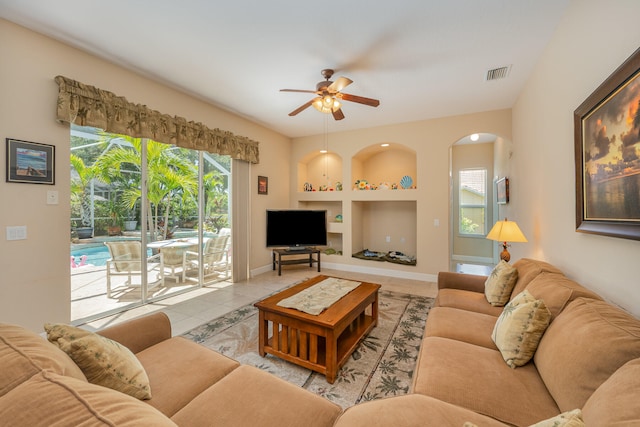 tiled living room featuring built in shelves and ceiling fan