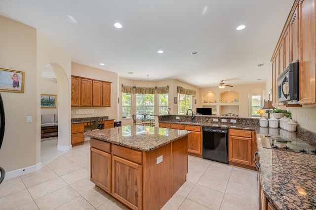 kitchen featuring kitchen peninsula, ceiling fan, black appliances, dark stone countertops, and a center island