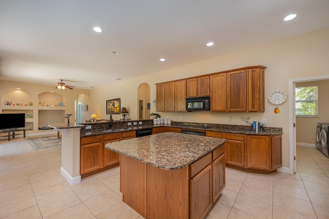 kitchen with kitchen peninsula, ceiling fan, black appliances, washer and dryer, and light tile patterned floors