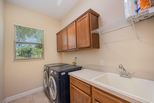 clothes washing area with cabinets, light tile patterned floors, sink, and washing machine and clothes dryer