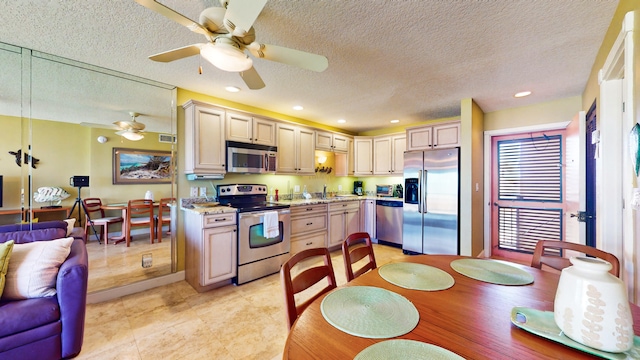 kitchen featuring a textured ceiling, appliances with stainless steel finishes, light stone counters, light tile flooring, and ceiling fan