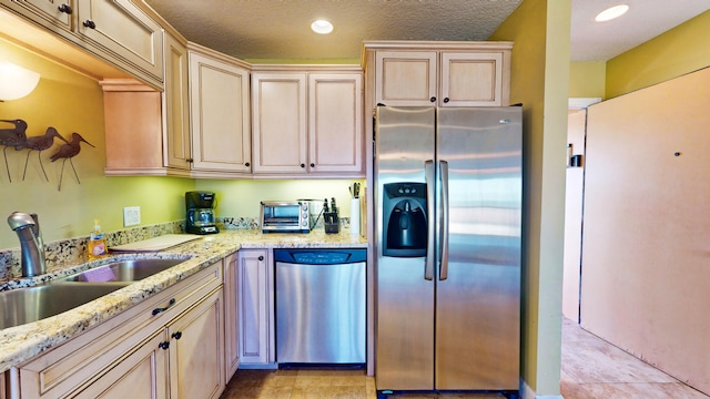 kitchen featuring appliances with stainless steel finishes, light stone countertops, sink, and light tile floors