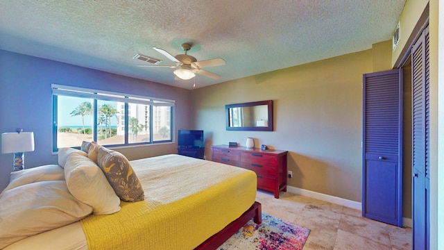 bedroom with tile flooring, a closet, ceiling fan, and a textured ceiling