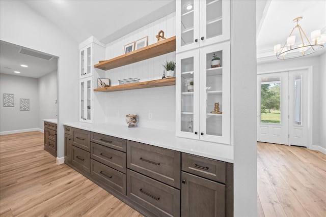 kitchen featuring an inviting chandelier, light hardwood / wood-style flooring, white cabinets, pendant lighting, and vaulted ceiling