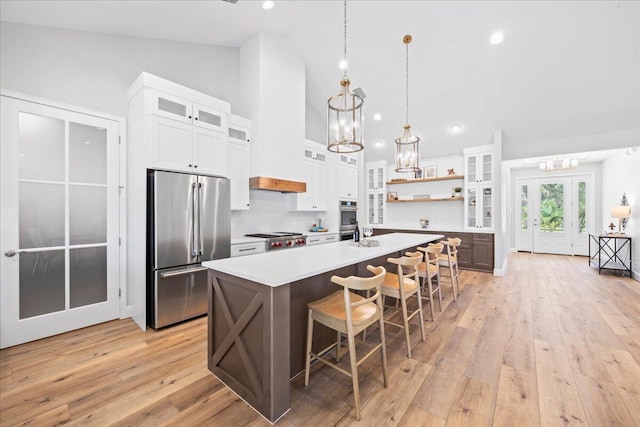 kitchen featuring light hardwood / wood-style floors, an island with sink, a breakfast bar area, white cabinetry, and appliances with stainless steel finishes