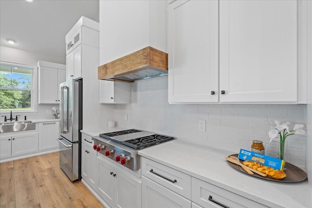 kitchen featuring stainless steel appliances, light hardwood / wood-style flooring, backsplash, and sink