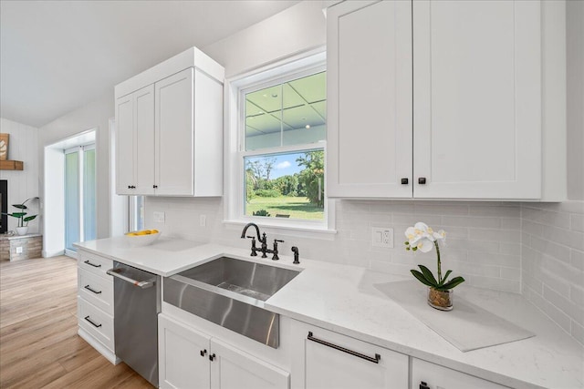 kitchen with white cabinetry, light wood-type flooring, backsplash, sink, and dishwasher