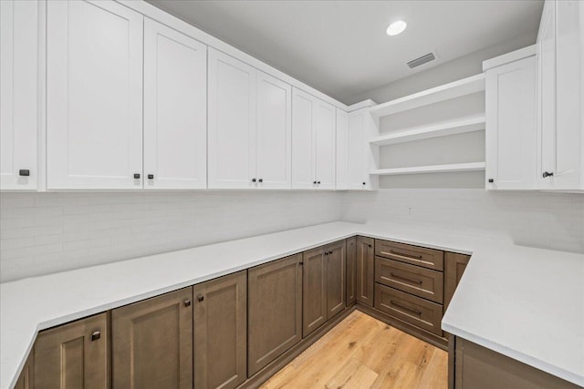 kitchen with light hardwood / wood-style floors, backsplash, and white cabinetry