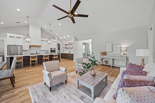 living room featuring high vaulted ceiling, ceiling fan, sink, and light hardwood / wood-style floors