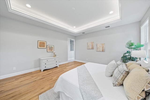 bedroom featuring hardwood / wood-style flooring, a raised ceiling, and crown molding