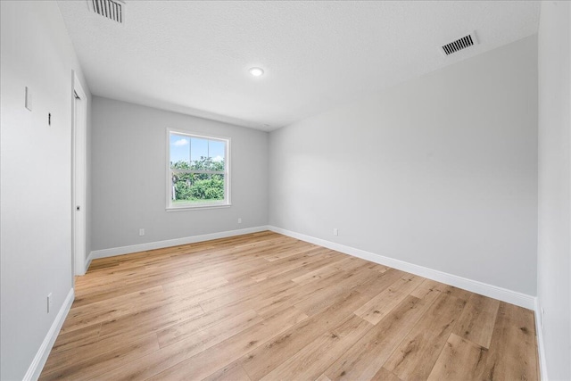 spare room with a textured ceiling and light wood-type flooring