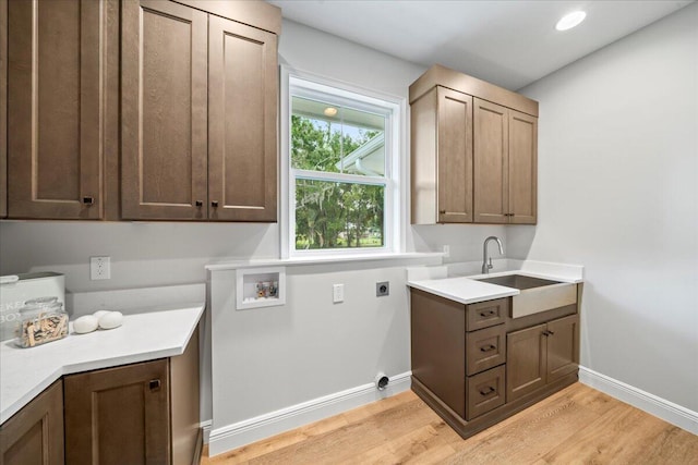 laundry area featuring cabinets, light hardwood / wood-style flooring, electric dryer hookup, hookup for a washing machine, and sink