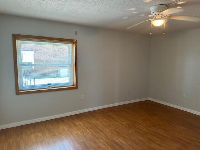 unfurnished room featuring wood-type flooring, a textured ceiling, and ceiling fan