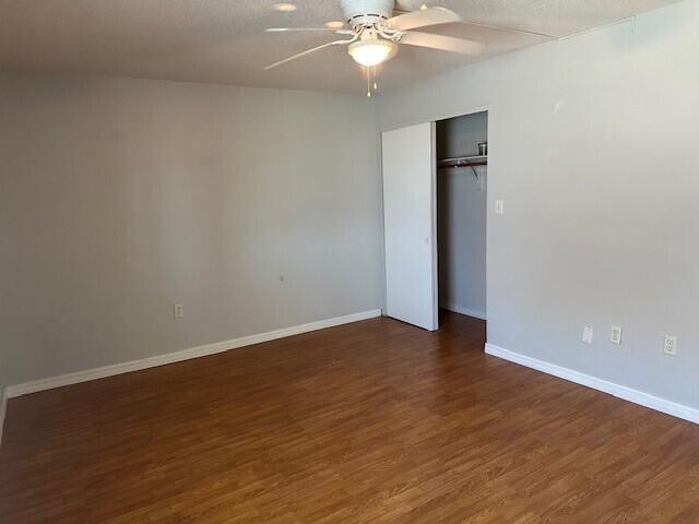 unfurnished bedroom with a textured ceiling, ceiling fan, a closet, and dark hardwood / wood-style floors