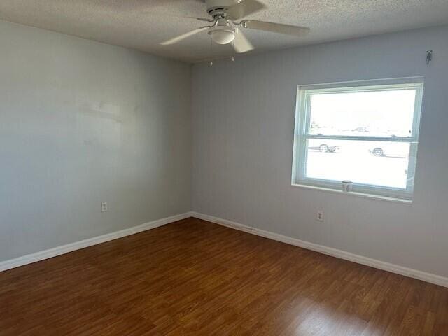 empty room with ceiling fan, dark hardwood / wood-style flooring, and a textured ceiling