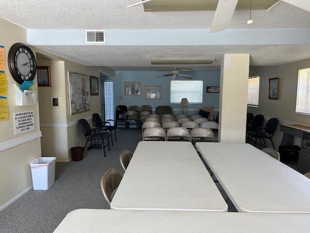 carpeted dining space featuring a textured ceiling and ceiling fan