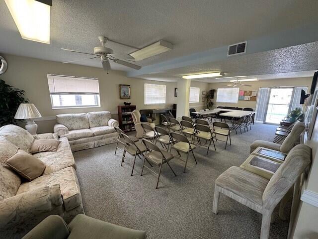 living room with carpet flooring, ceiling fan, and a textured ceiling