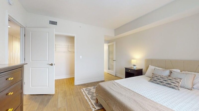 bedroom featuring a spacious closet, a closet, and light hardwood / wood-style floors