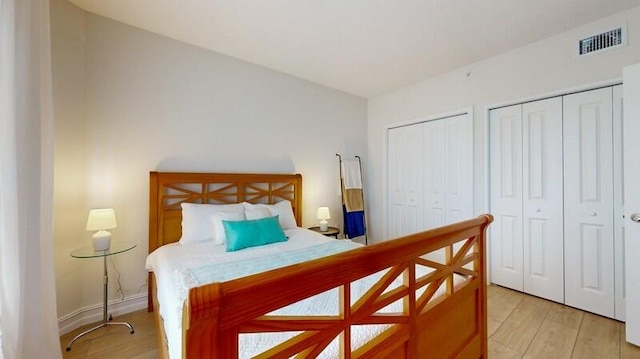 bedroom featuring light hardwood / wood-style floors and two closets