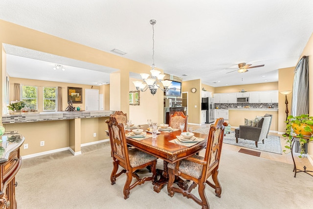 carpeted dining space featuring ceiling fan with notable chandelier