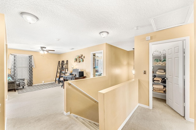 hallway featuring a textured ceiling and light carpet