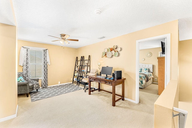 carpeted office featuring ceiling fan and a textured ceiling