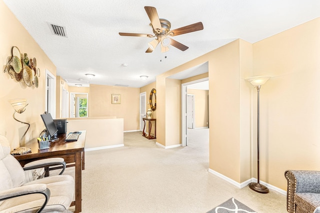 carpeted office space with a textured ceiling and ceiling fan