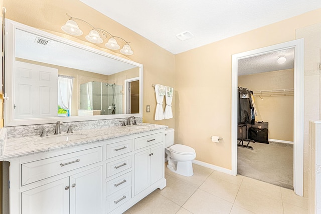 bathroom with vanity, tile patterned floors, toilet, a textured ceiling, and a shower with shower door