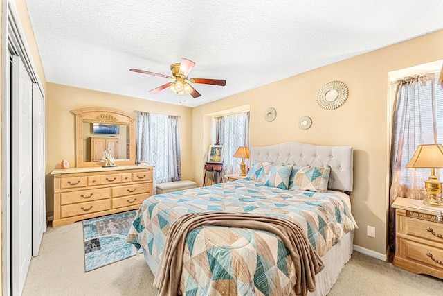 carpeted bedroom with ceiling fan, a closet, and a textured ceiling