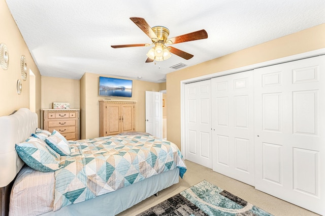 bedroom featuring light carpet, a textured ceiling, a closet, and ceiling fan