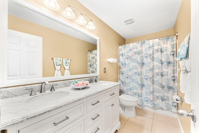 bathroom featuring tile patterned floors, vanity, toilet, and a textured ceiling