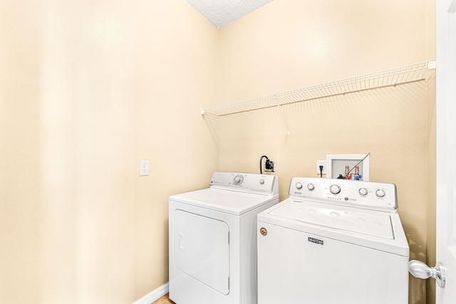 laundry area with a textured ceiling and washing machine and clothes dryer