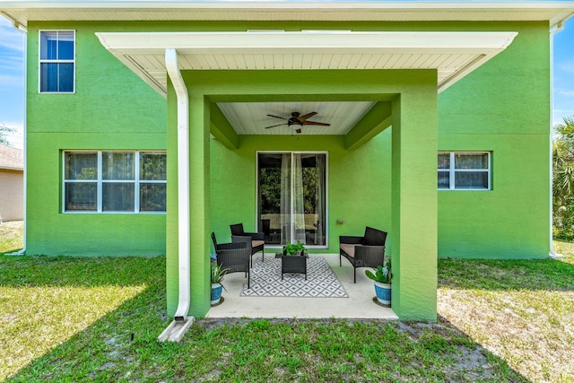 rear view of property featuring a lawn, ceiling fan, a patio area, and an outdoor hangout area