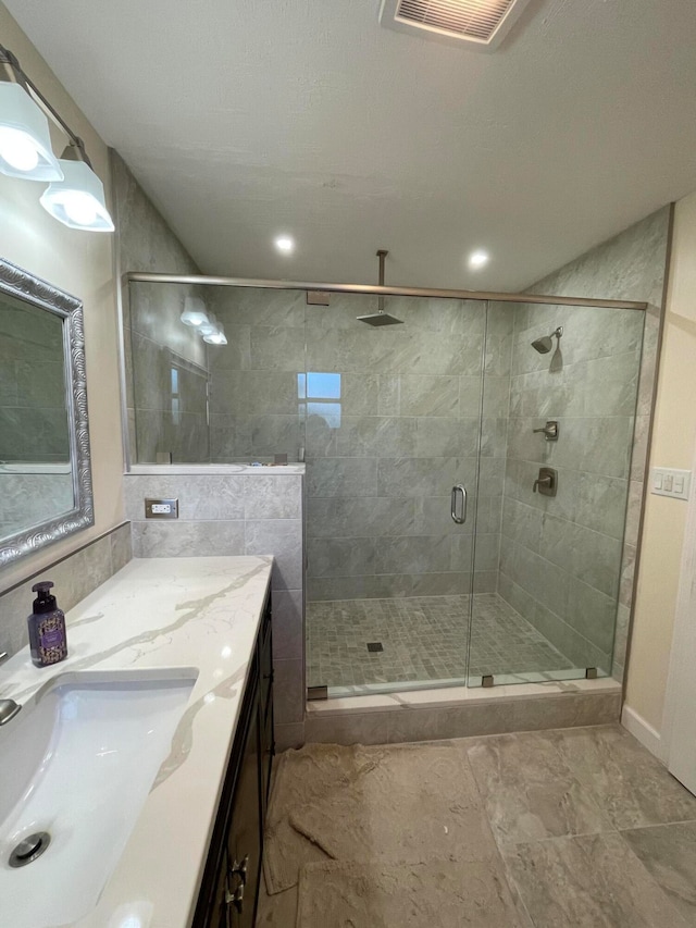 bathroom with a shower with shower door and vanity