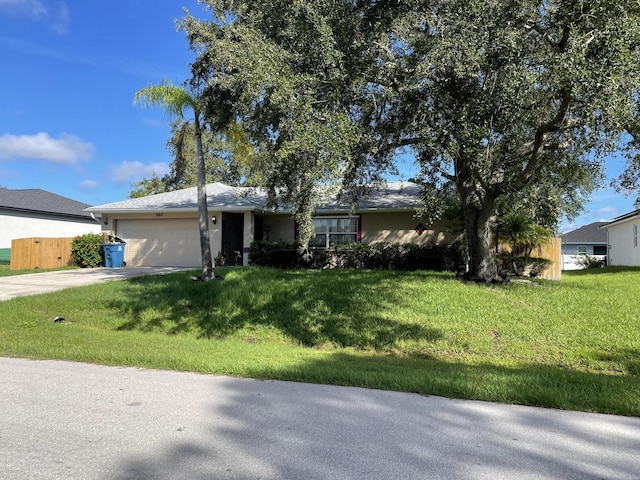 ranch-style home featuring a front yard, concrete driveway, fence, and an attached garage