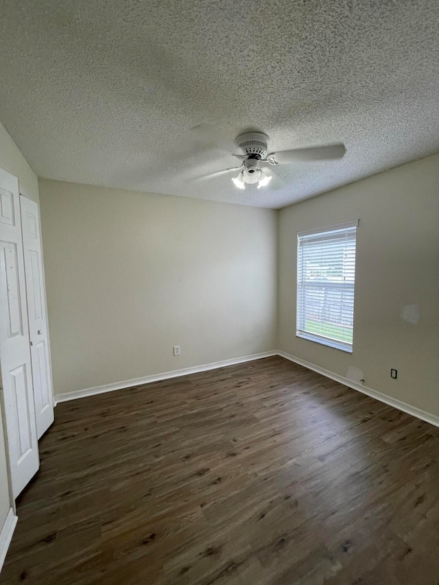 spare room with ceiling fan, dark wood-type flooring, and a textured ceiling