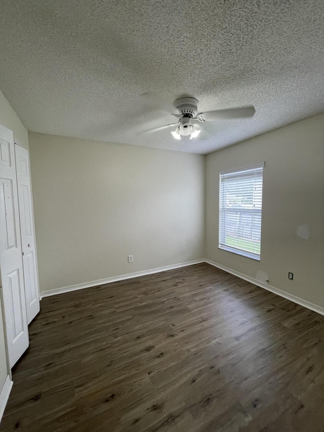 spare room with ceiling fan, dark wood-type flooring, a textured ceiling, and baseboards