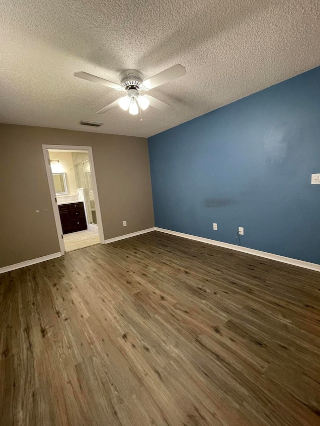 unfurnished bedroom featuring ceiling fan, dark hardwood / wood-style floors, ensuite bathroom, and a textured ceiling