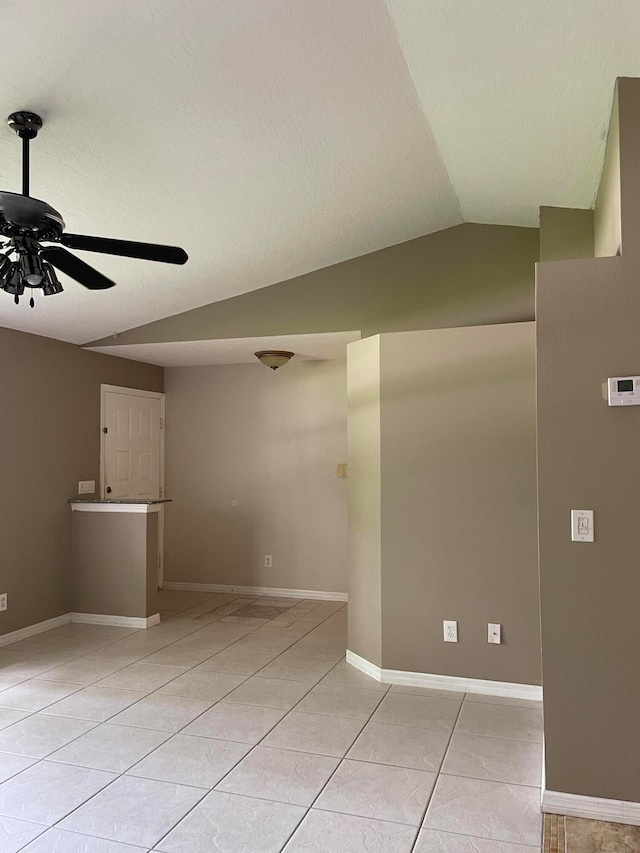 tiled empty room featuring vaulted ceiling and ceiling fan