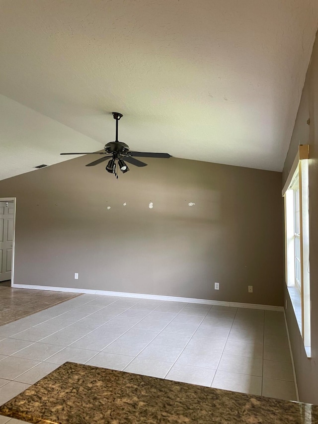 spare room featuring ceiling fan, lofted ceiling, and light tile patterned flooring