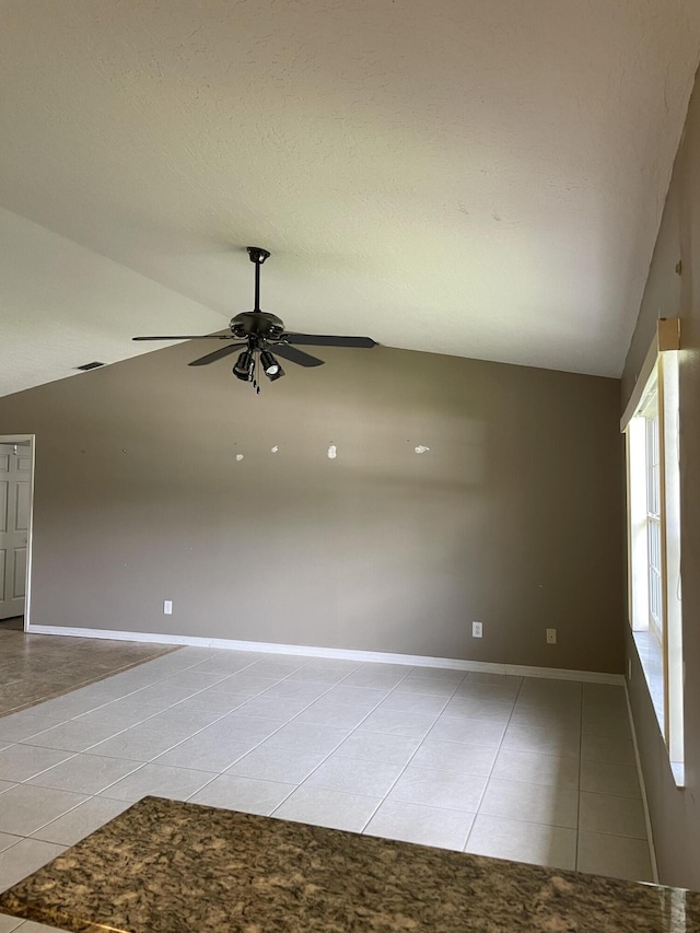 empty room with light tile patterned floors, lofted ceiling, ceiling fan, a textured ceiling, and baseboards