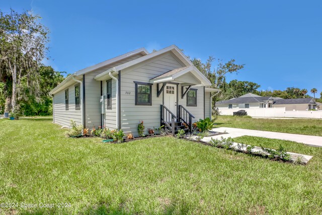 702 S Myrtle Ave, New Smyrna Beach, FL 32168 - bungalow-style home with fence, a front lawn, and entry steps