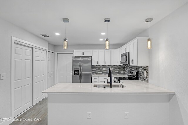 702 S Myrtle Ave, New Smyrna Beach, FL 32168 - kitchen with a sink, appliances with stainless steel finishes, a peninsula, white cabinets, and decorative backsplash