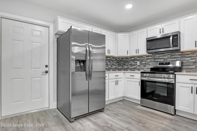 702 S Myrtle Ave, New Smyrna Beach, FL 32168 - kitchen with light countertops, appliances with stainless steel finishes, light wood-style flooring, and decorative backsplash